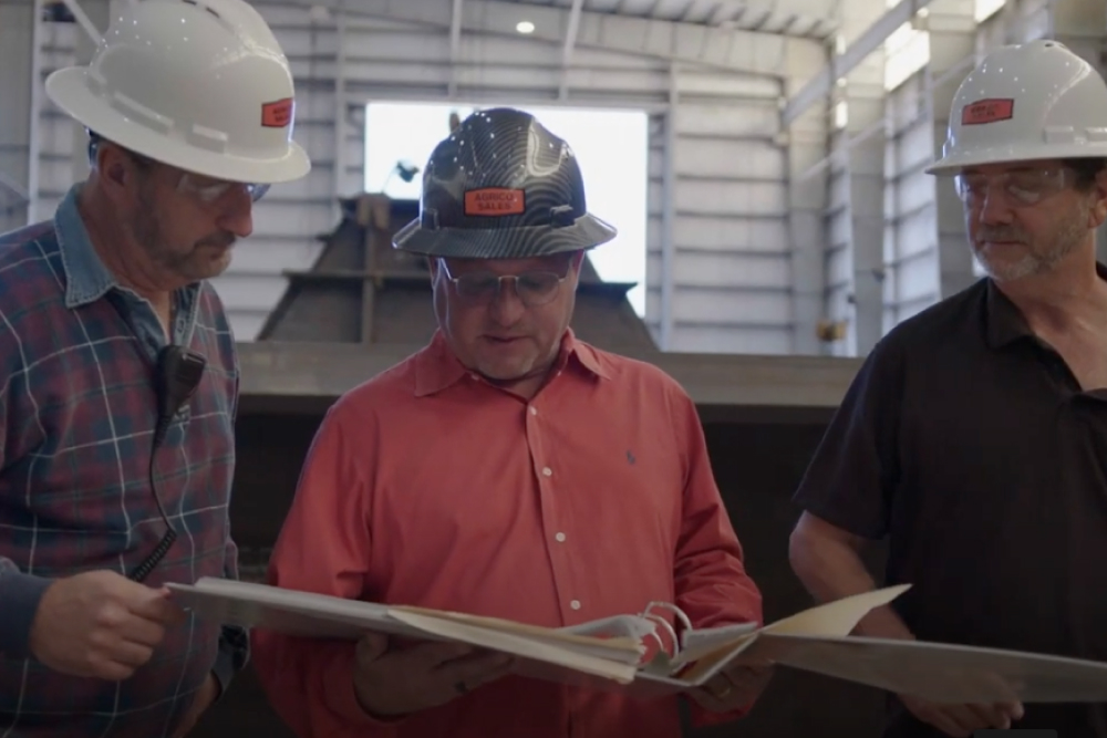 Three men in hardhats reviewing building plans